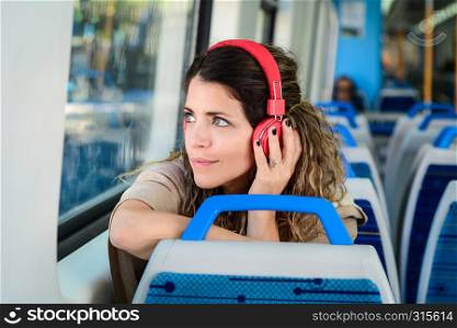 Young woman travelling by train with red headphones.