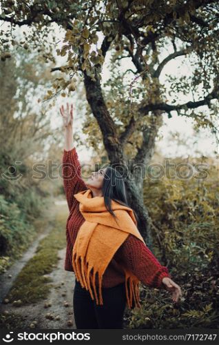 Young woman trying to catch a pear from tree