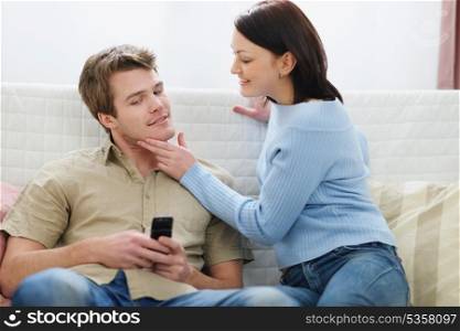 Young woman trying to distract boyfriend from mobile phone