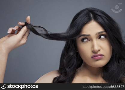 Young woman twisting hair finger over colored background