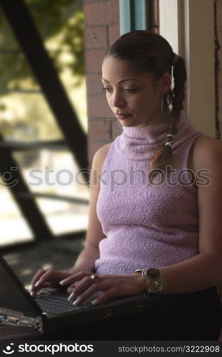 Young Woman Typing at a Windowsill