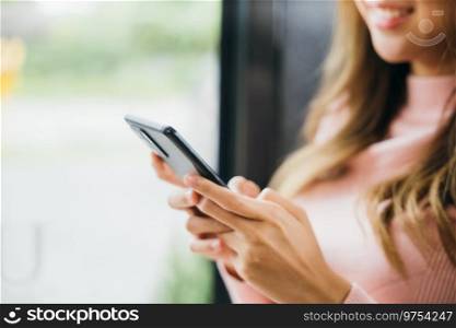 Young woman typing text message on smart phone device apps in cafe, beautiful female holding cellphone in hands and chatting social network with friends or reading email, mobile phone