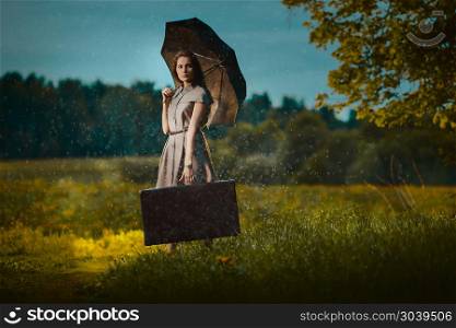 Young woman under rain. Young woman walking away with a suitcase under rain