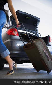 Young woman unloading luggage from car