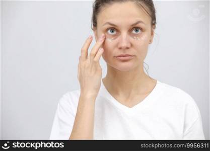 young woman uses eye cream. Girl care of healthy clean skin use spa treatment lotion. Closeup portrait.. young woman uses eye cream. Girl care of healthy clean skin use spa treatment lotion. Closeup portrait