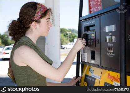 Young woman uses her credit card to pay for gasoline at the pump.