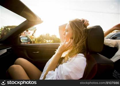 Young woman uses  mobile phone and sitting in cabriolet at summer day