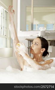 Young woman using a bath sponge on her arm