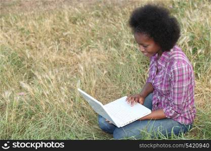 Young woman using a laptop in a field