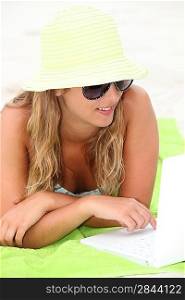 Young woman using a laptop on a beach