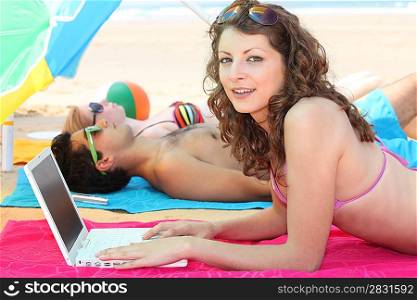 Young woman using a laptop on the beach