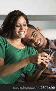 Young woman using a mobile phone and a young man leaning on her shoulder