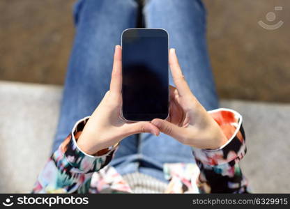 Young woman using a touchscreen smartphone wearing casual clothes