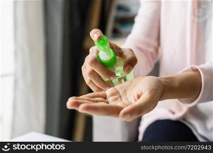 Young woman using alcohol gel sanitizer pump to avoid infections corona virus and bacteria