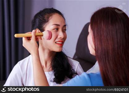 young woman using brush makeup on face her friend