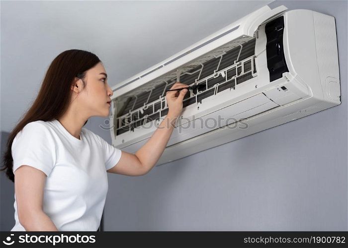 young woman using brush to cleaning the air conditioner indoors at hone