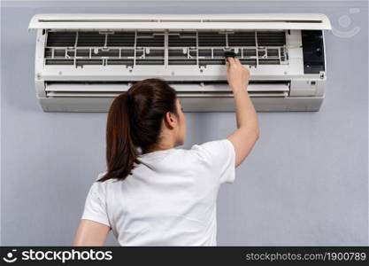 young woman using brush to cleaning the air conditioner indoors at hone