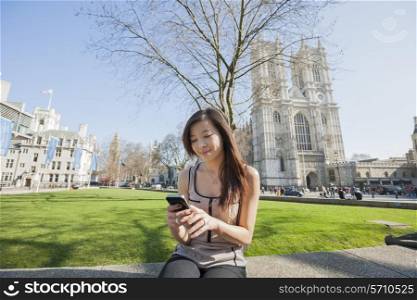 Young woman using cell phone against Westminster Abbey in London; England; UK