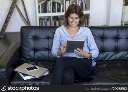 Young woman using digital tablet at home. Attractive young woman holding a tablet at home