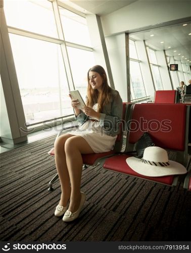 Young woman using digital tablet while waiting for airplane departure