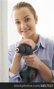 Young Woman Using Electric Drill In House Renovation Project