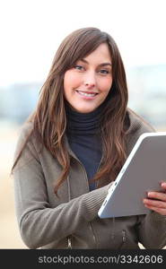 Young woman using electronic pad by the beach in winter