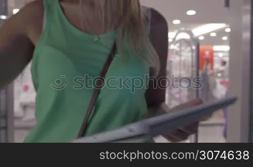 Young woman using elevator to get to another floor of hypermarket. She using tablet computer while riding up in the lift