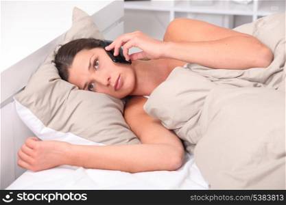 Young woman using her cellphone in bed