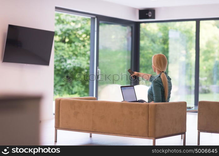 Young woman using her laptop computer in her luxury modern home, smiling