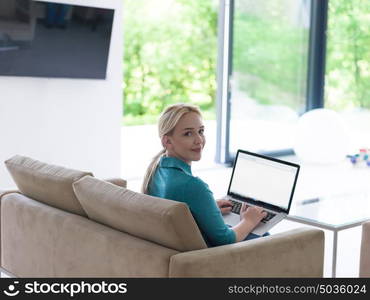 Young woman using her laptop computer in her luxury modern home, smiling