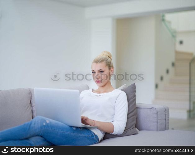 Young woman using her laptop computer in her luxury modern home, smiling