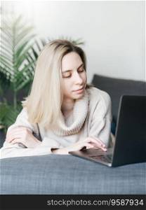 Young woman  using laptop computer at home sitting comfortably  in living room. 