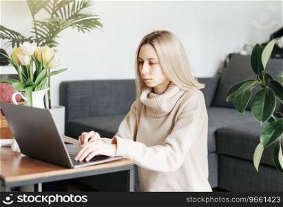 Young woman  using laptop computer at home sitting comfortably on a floor in living room. 
