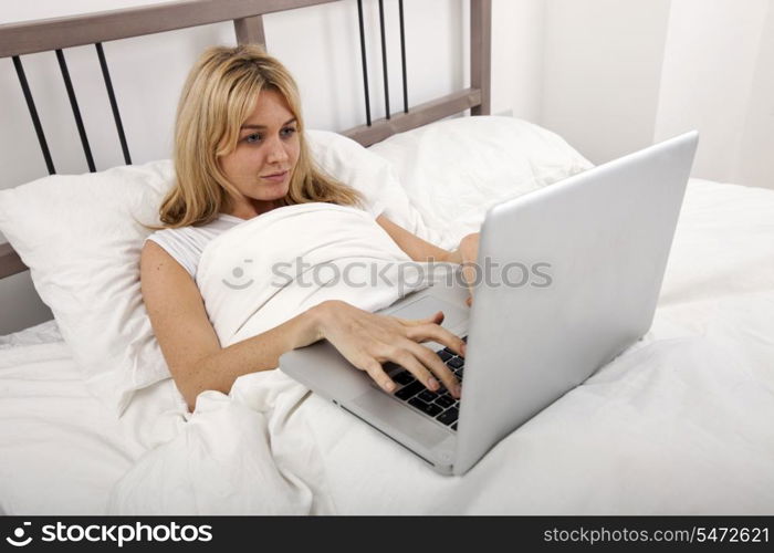Young woman using laptop in bed