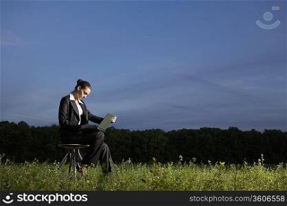 Young woman using laptop in field