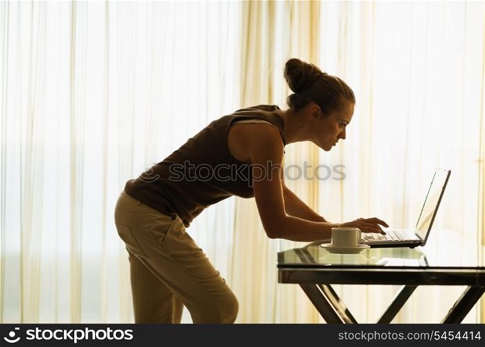 Young woman using laptop leaning against table