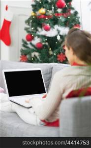 Young woman using laptop near christmas tree . rear view