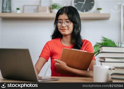 young woman using laptop on desk and holding files