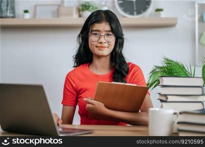 young woman using laptop on desk and holding files