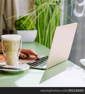 Young woman using laptop with dessert and cup of coffee in cafe