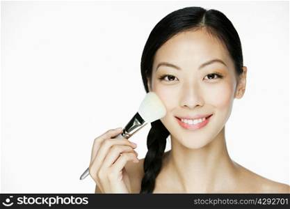 Young woman using makeup brush