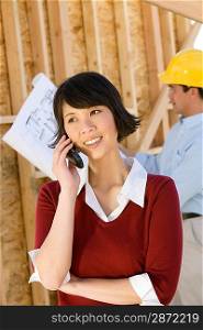 Young woman using mobile phone in construction site