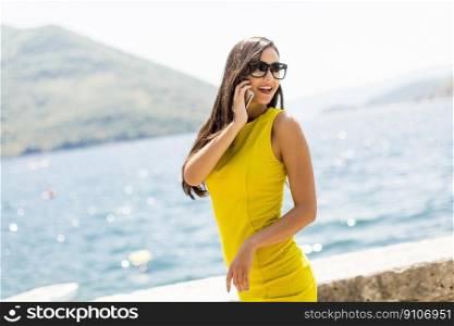 Young woman using mobile telephone by the sea