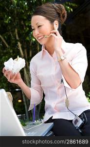 Young woman using mobile while eating sandwich