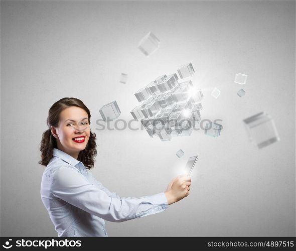 Young woman using modern technologies. Young woman holding tablet and looking at camera and cubes coming out of screen
