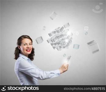 Young woman using modern technologies. Young woman holding tablet and looking at camera and cubes coming out of screen