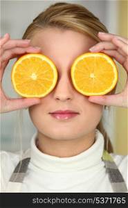 Young woman using orange halves as eyes