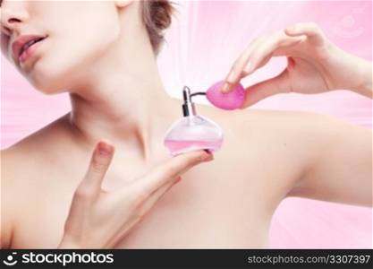 Young woman using perfume on abstract background