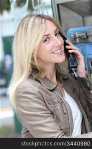 Young woman using public phone