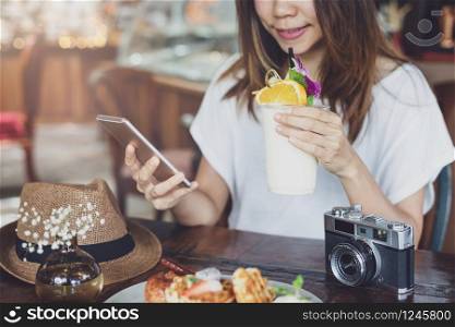 Young woman using smart phone and enjoy eating dessert in cafe on vacation trip. Young woman using smart phone and enjoy eating dessert in cafe on vacation